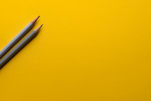 Two pencils on a yellow surface